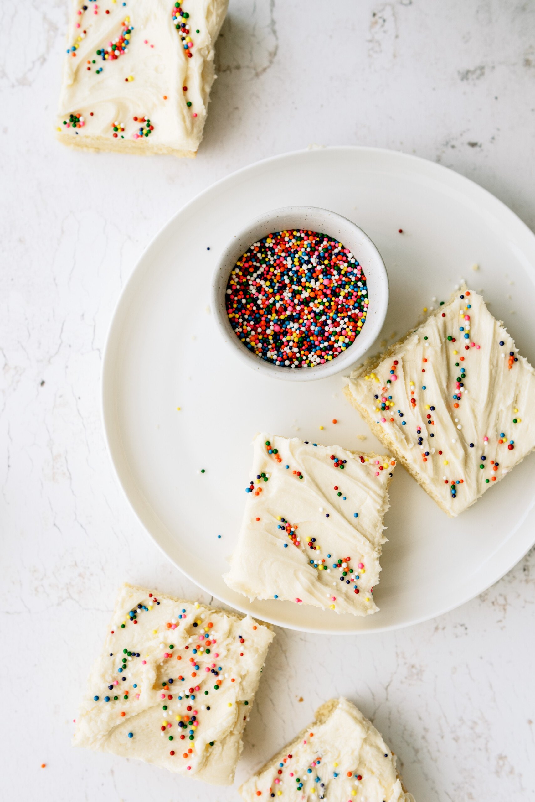 top down view of cookie bars on a plate next to a small bowl of sprinkles
