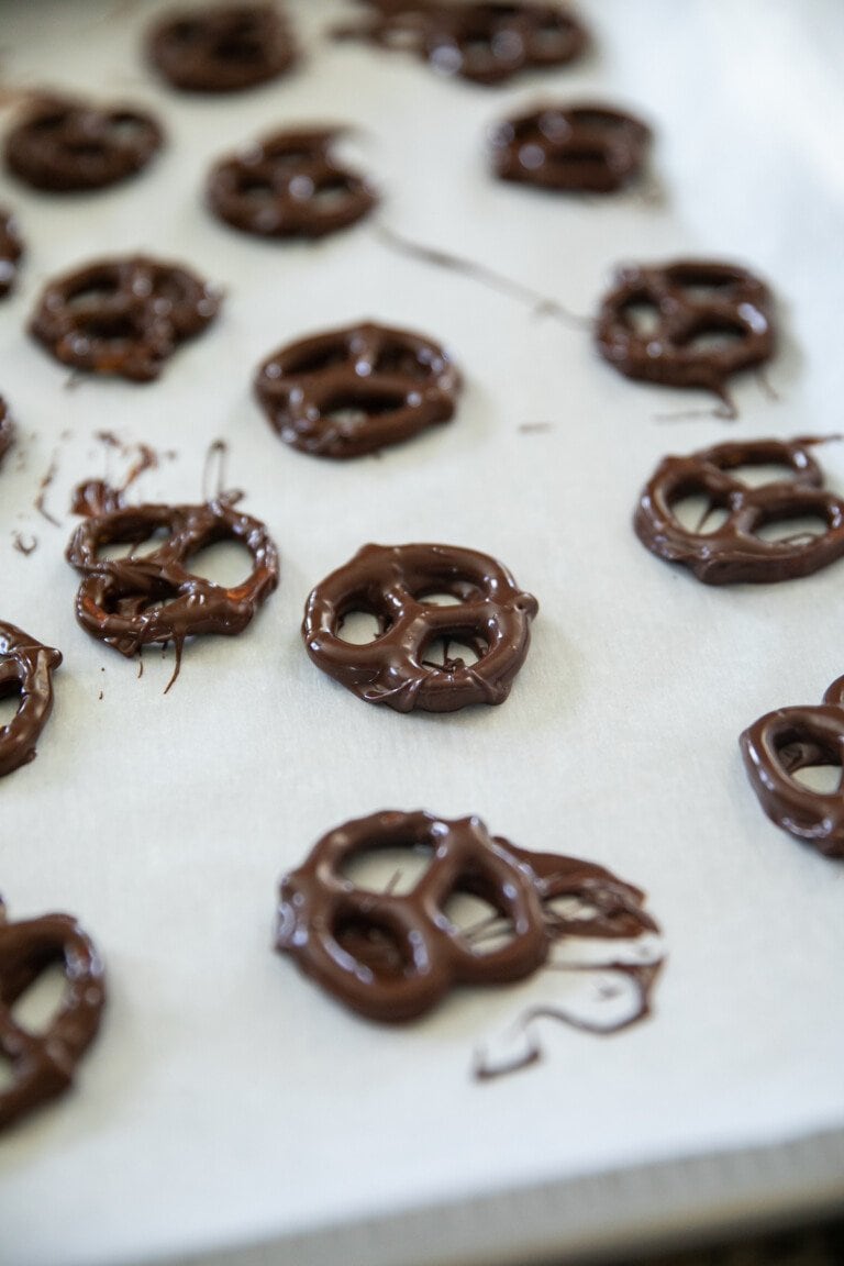 chocolate covered pretzels on a wax paper lined baking sheet