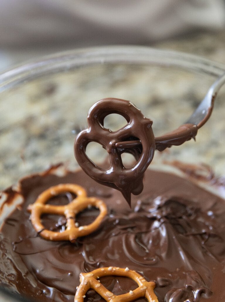 pulling chocolate covered pretzel out of melted chocolate