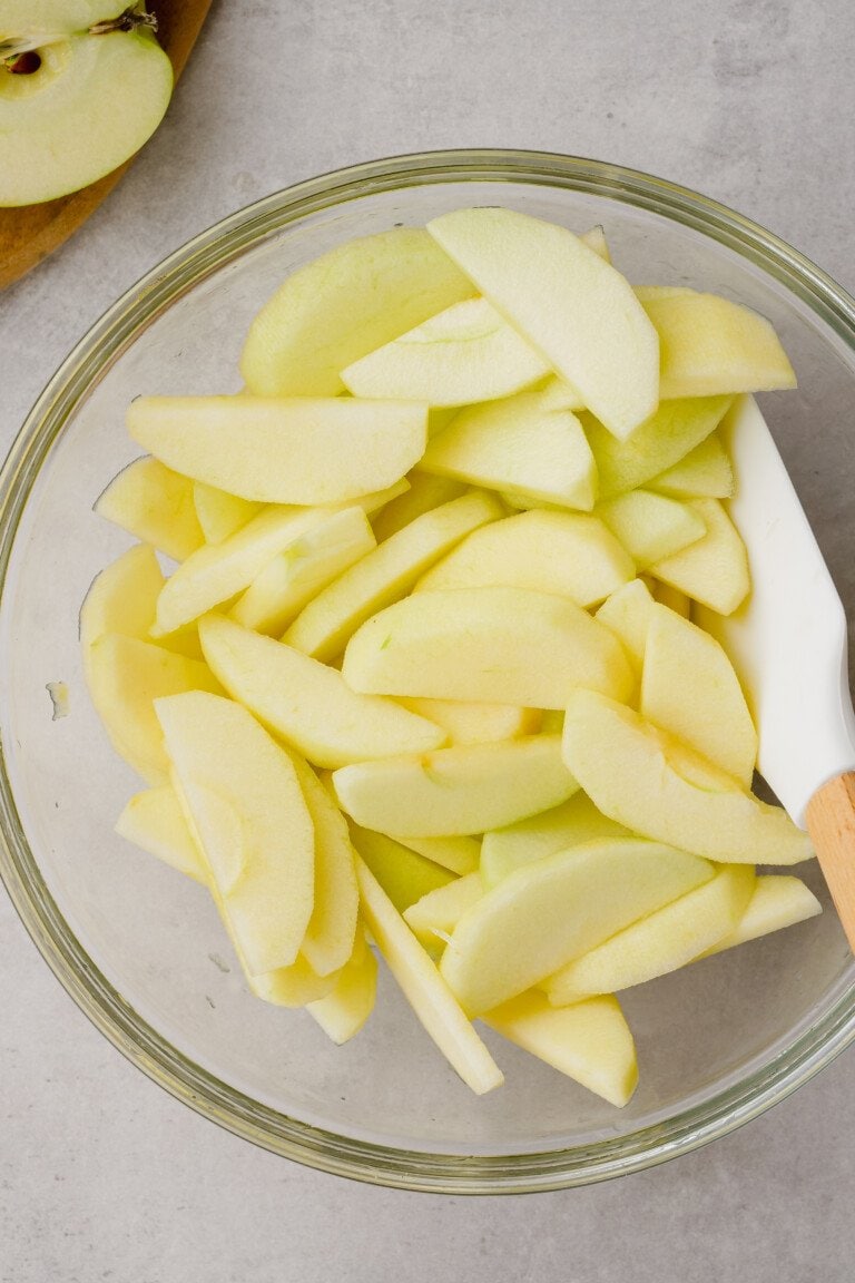 peeled and sliced apples in a glass bowl