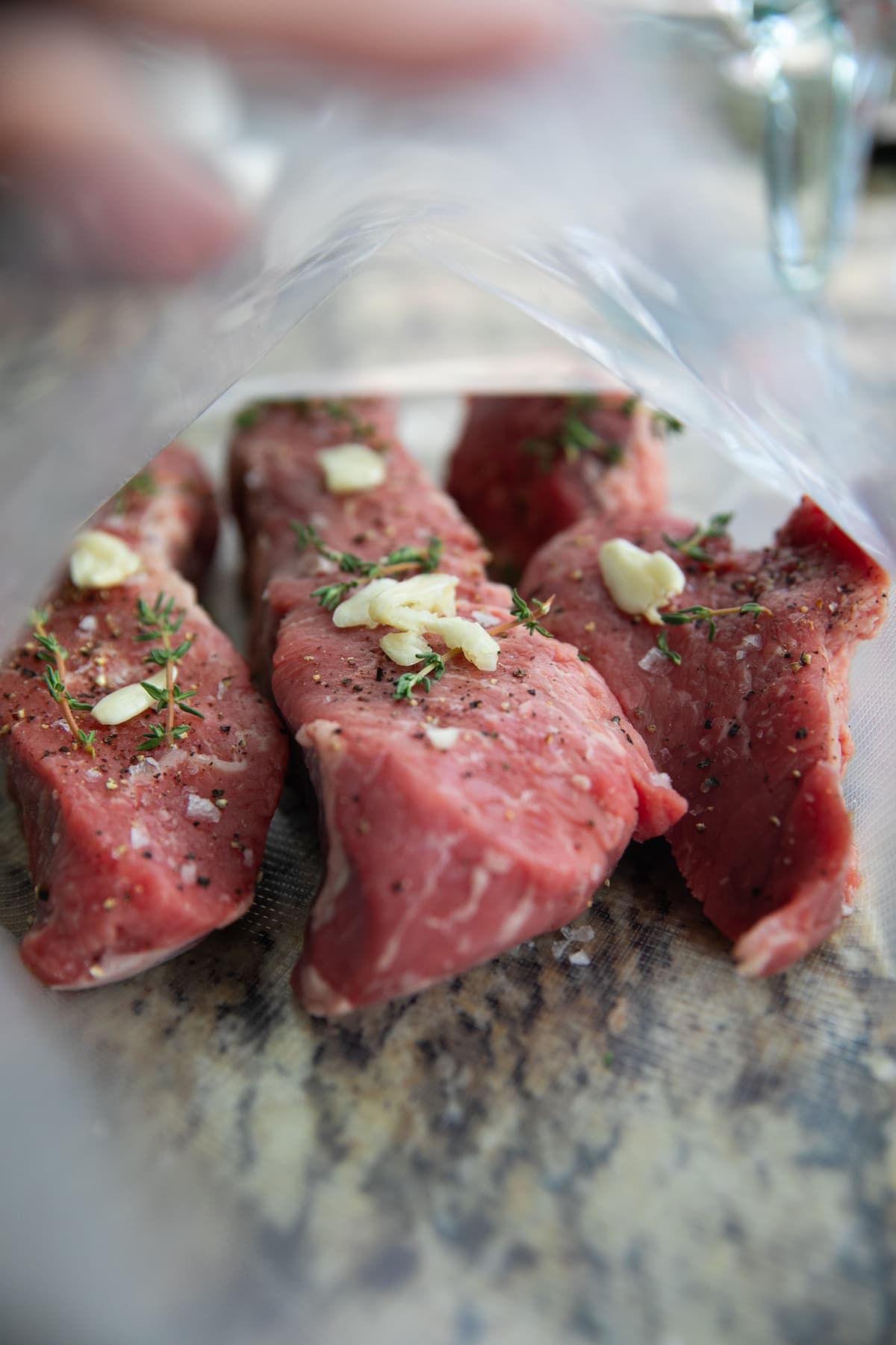 raw steaks in bag with garlic and herbs