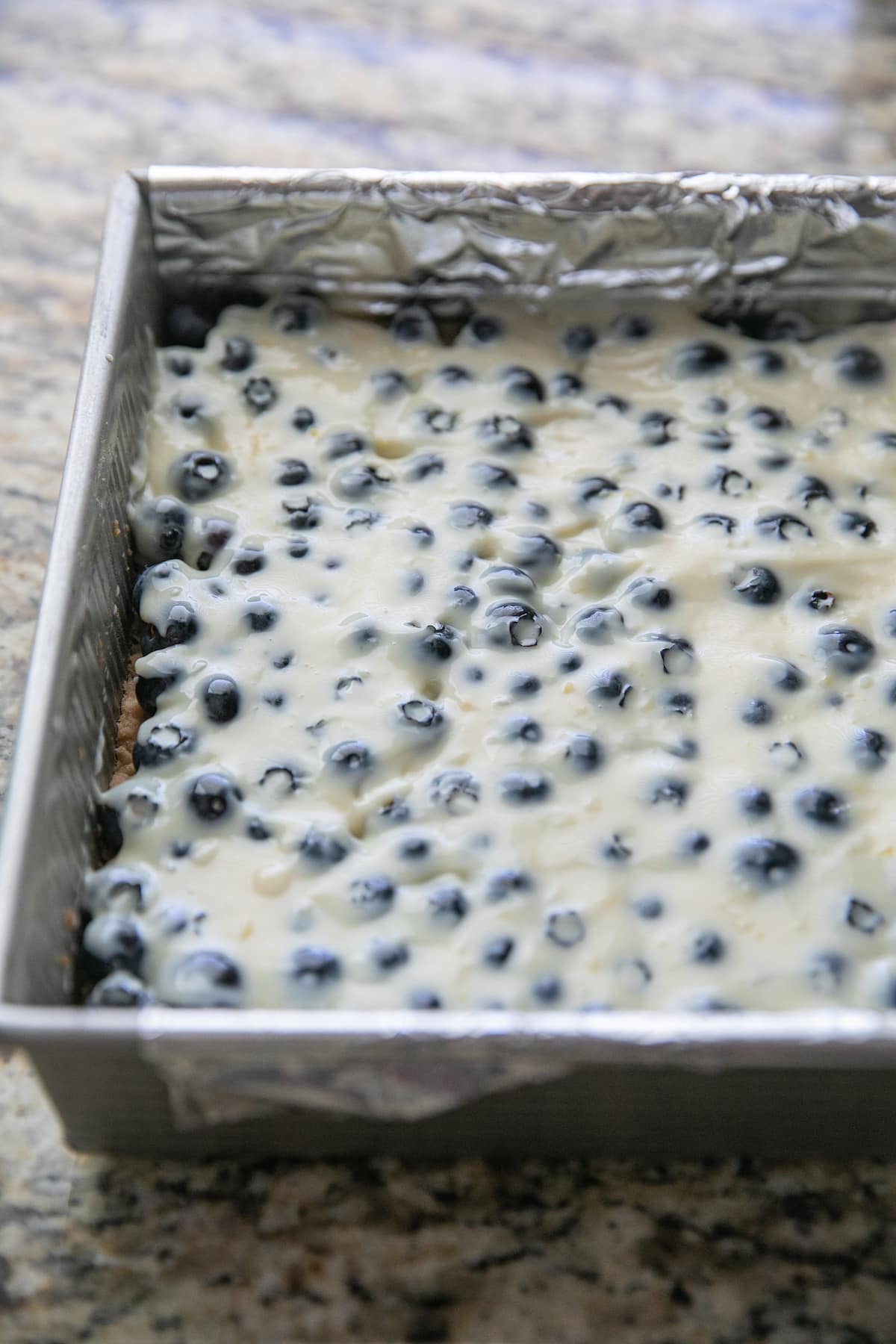 lemon mixture covering blueberries in a baking pan, unbaked