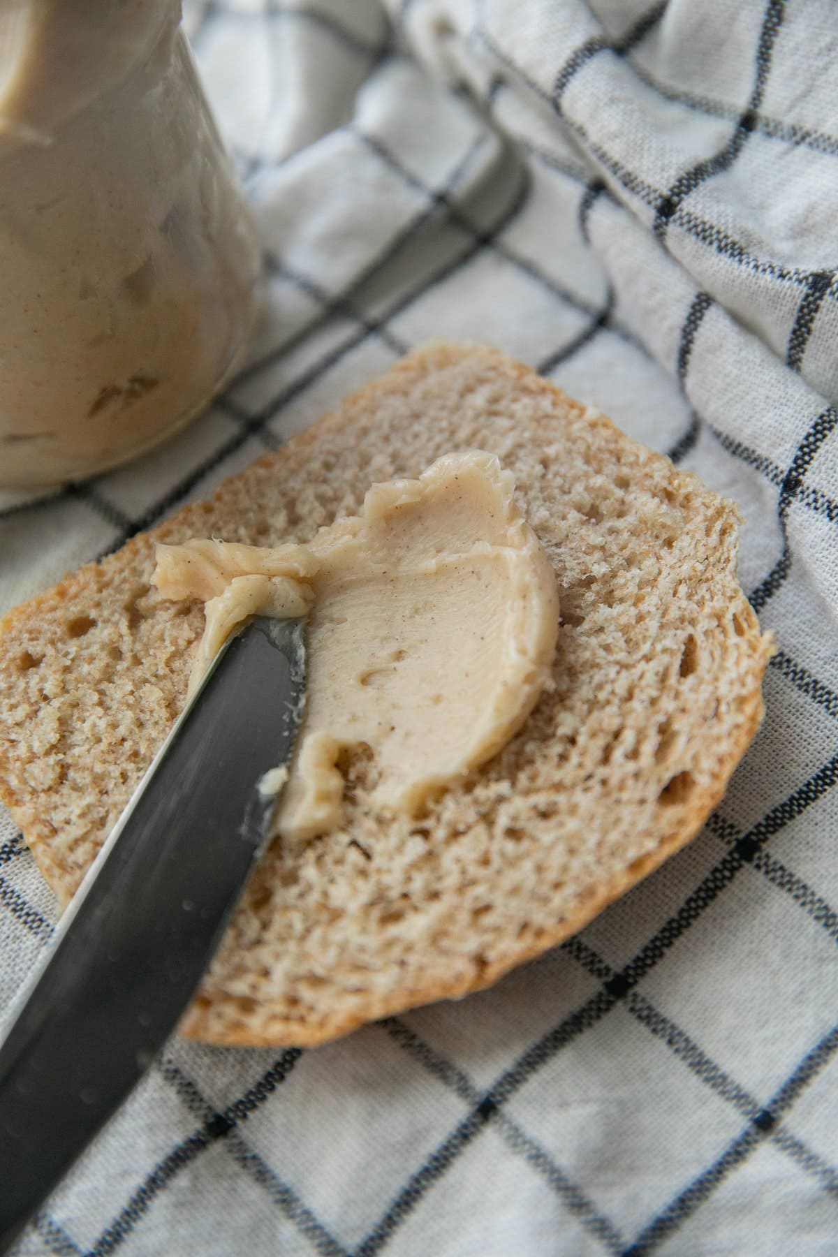 honey butter being slathered onto a piece of whole wheat bread with a butter knife