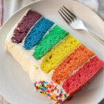 slice of rainbow cake on white plate with fork