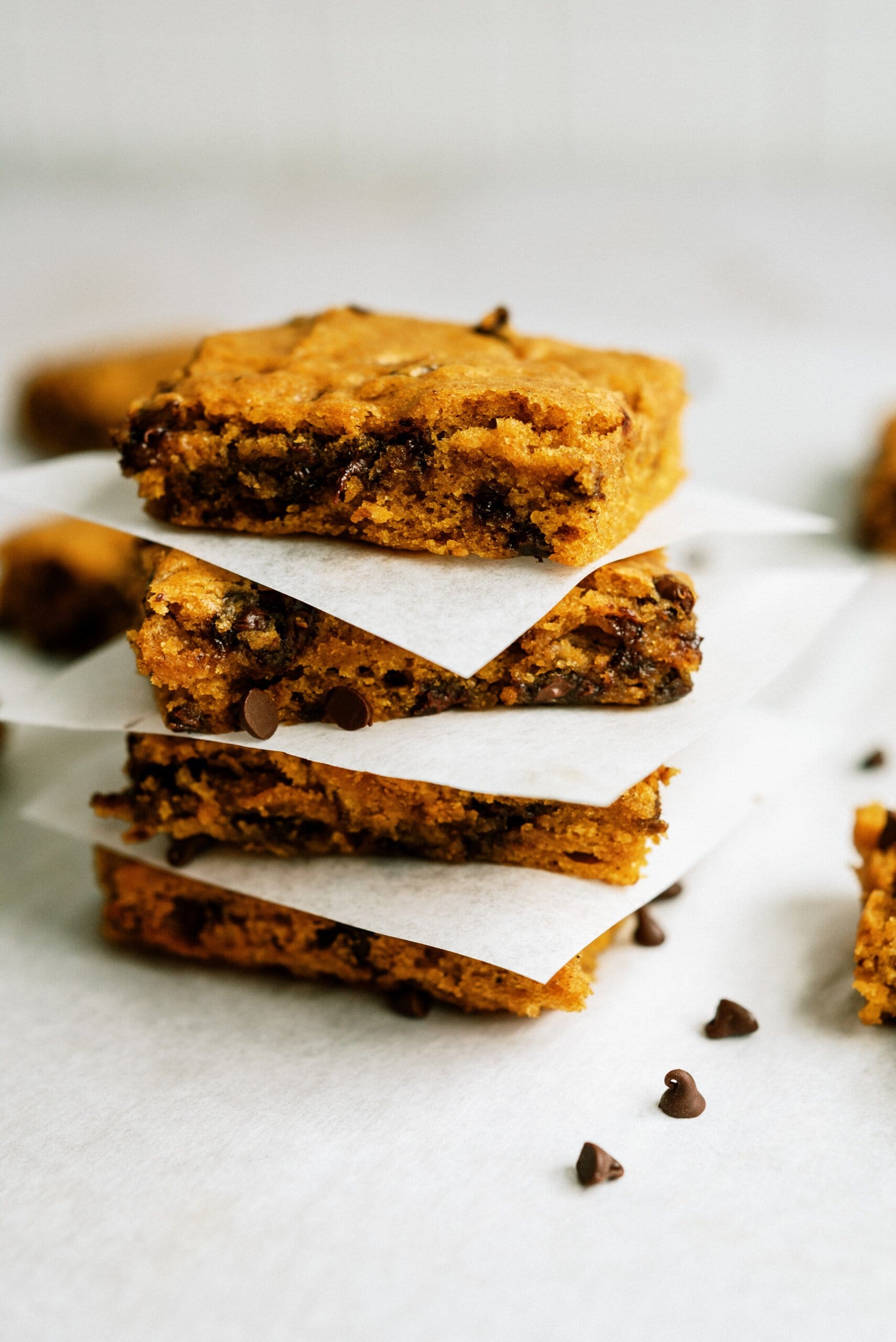 pumpkin chocolate chip bars stacked on top of each other with parchment paper in-between them