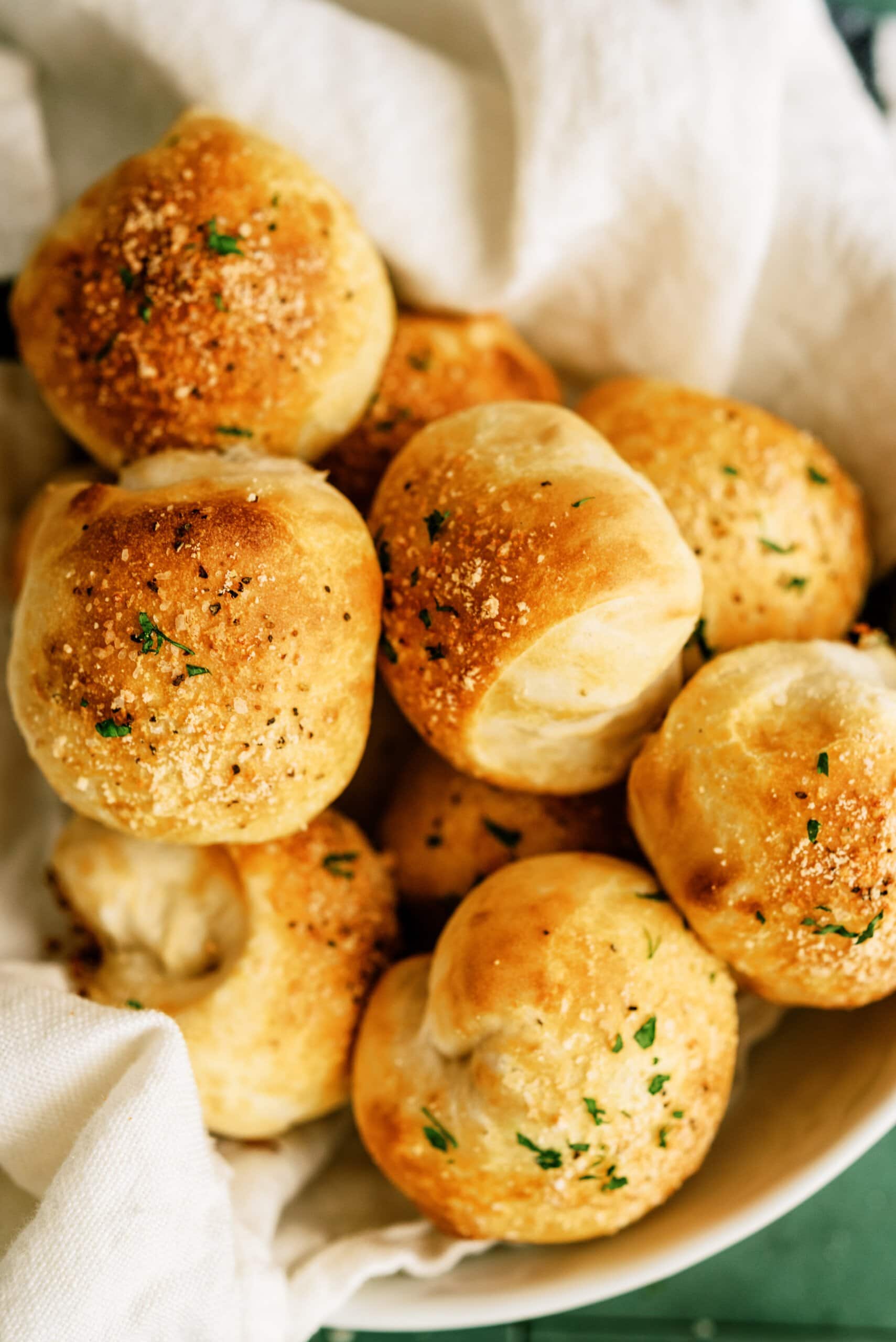 close up of parmesan bread bites in a bowl lined with