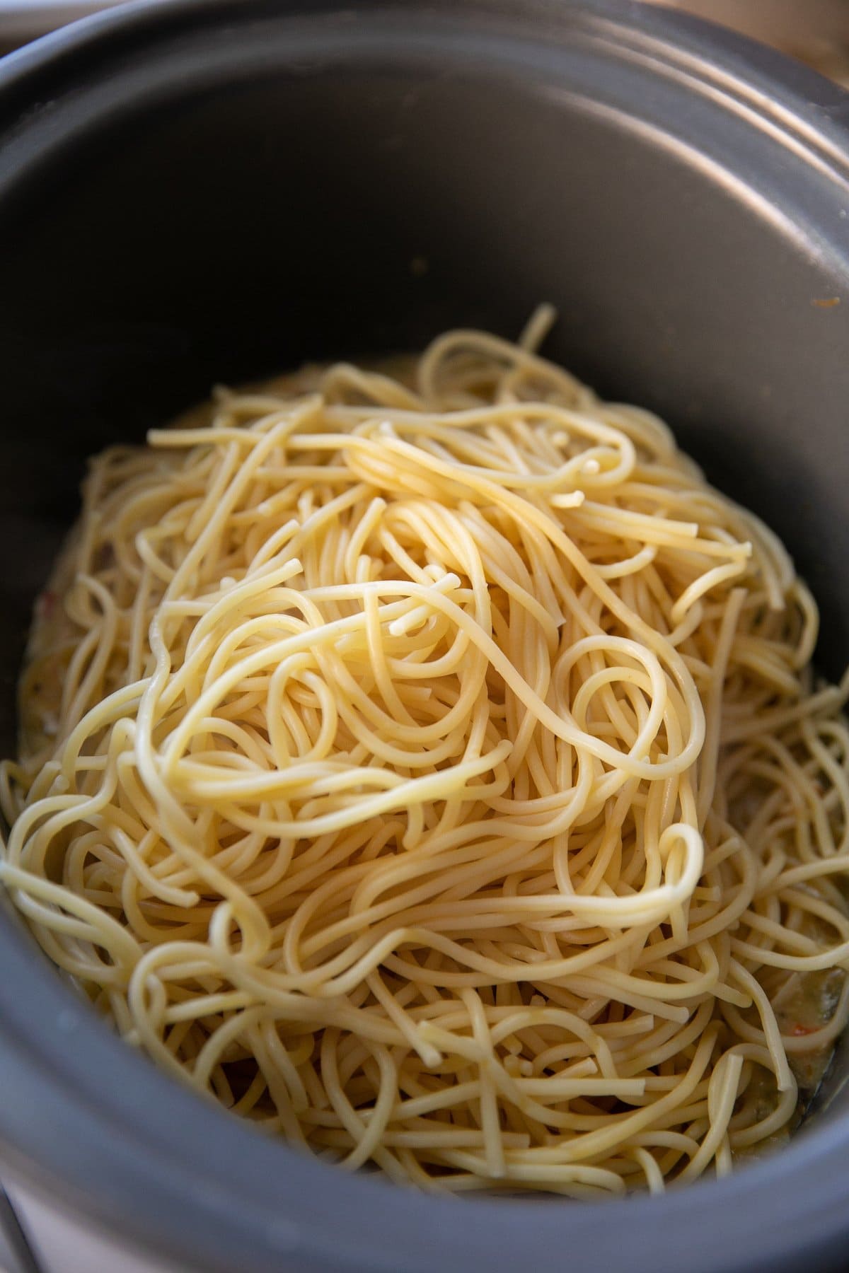 adding cooked spaghetti noodles to the pot