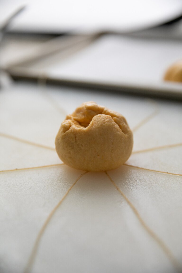 small dough ball placed in the middle of wet bakers string criss crossing
