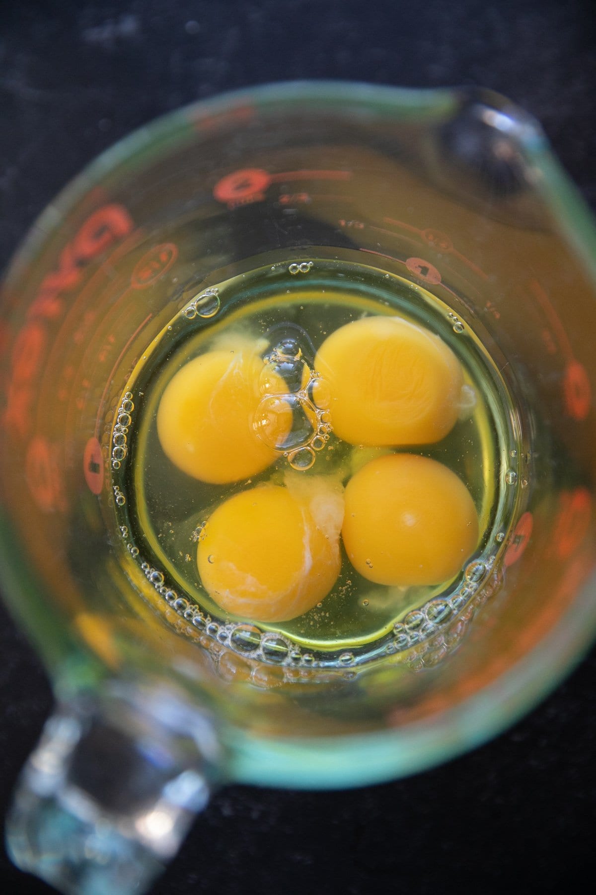 four cracked eggs in a measuring cup