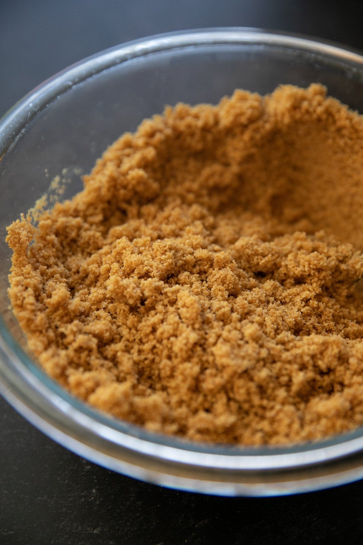 graham cracker crumbs mixed with butter and sugar in a glass bowl