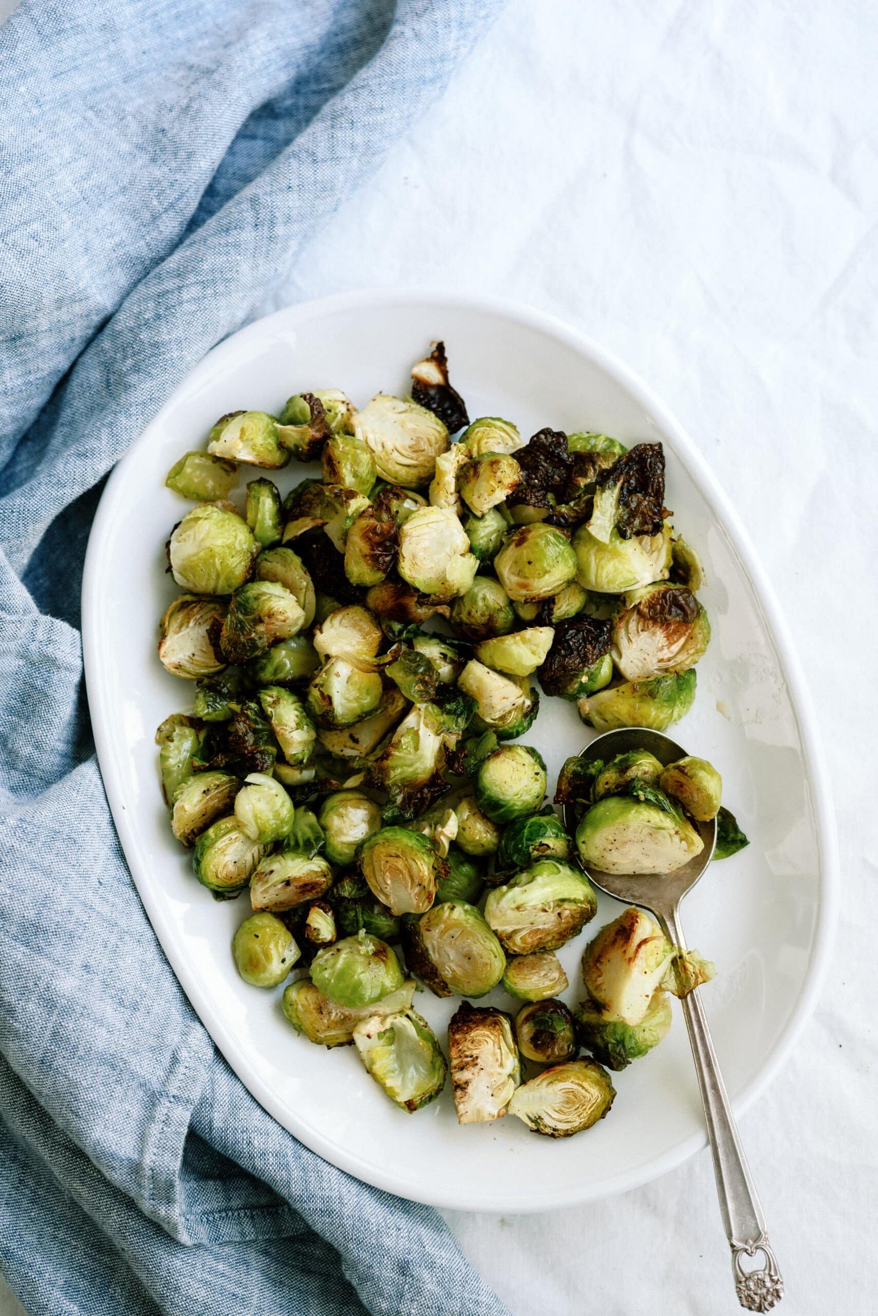 Top view of roasted Brussels sprouts on a white serving plate
