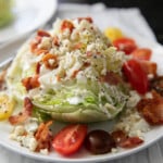 wedge salad with toppings and dressing on a white plate