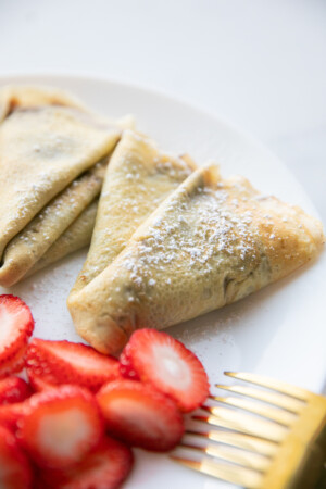filled nutella crepes on plate with strawberries