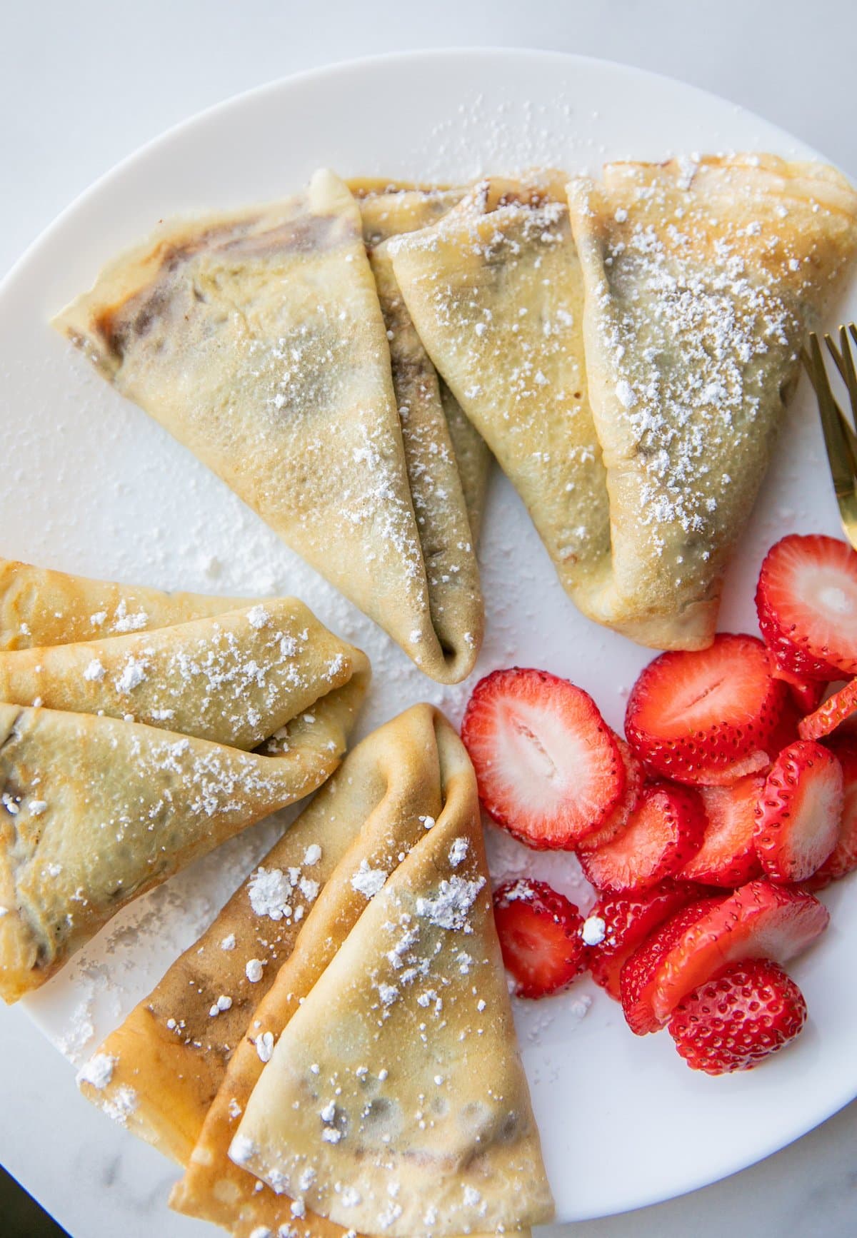 filled nutella crepes on plate with strawberries