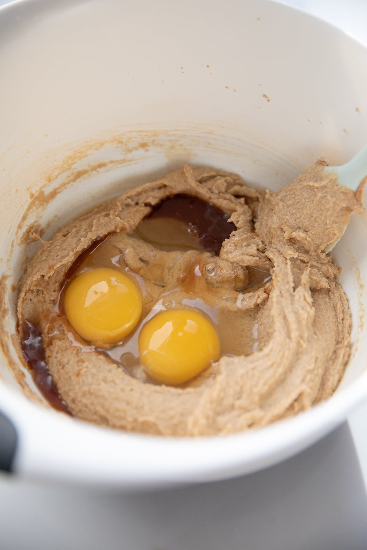 adding eggs and vanilla to peanut butter oatmeal cookie dough