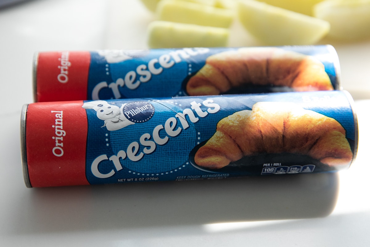 two cans of crescent rolls on cutting board