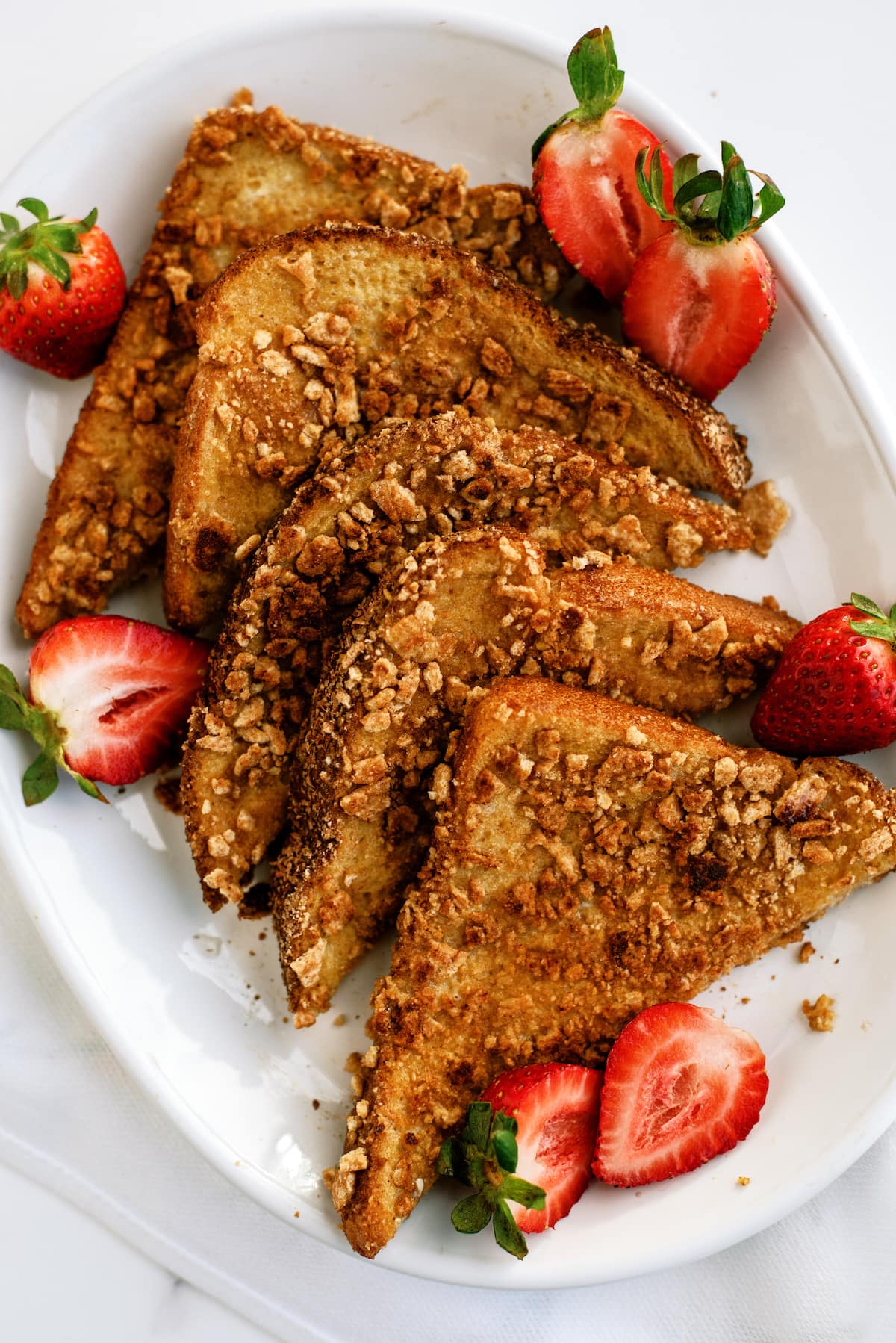 Cinnamon Toast Crunch French toast sliced on a plate with strawberries