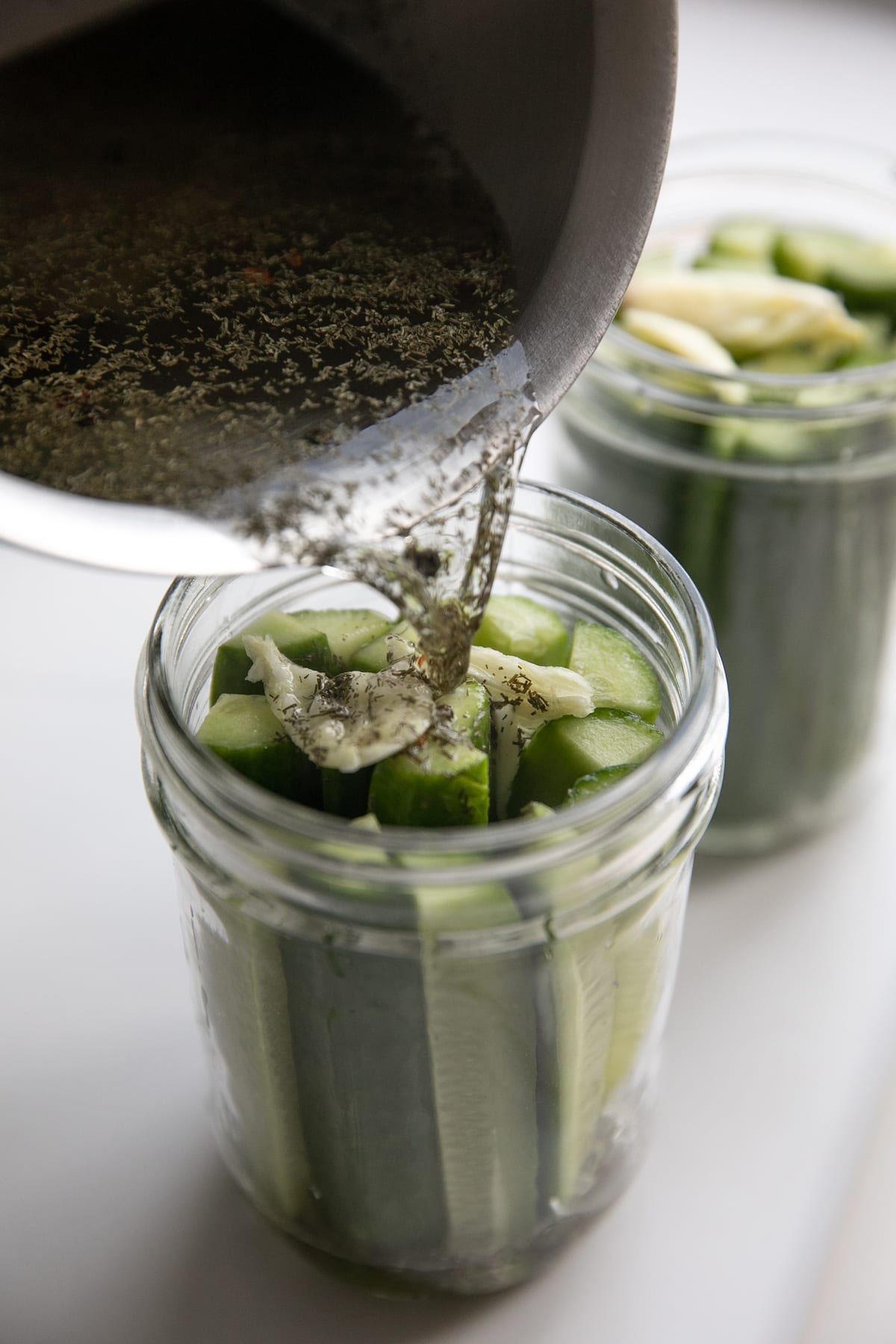 pouring pickling liquid over cucumbers