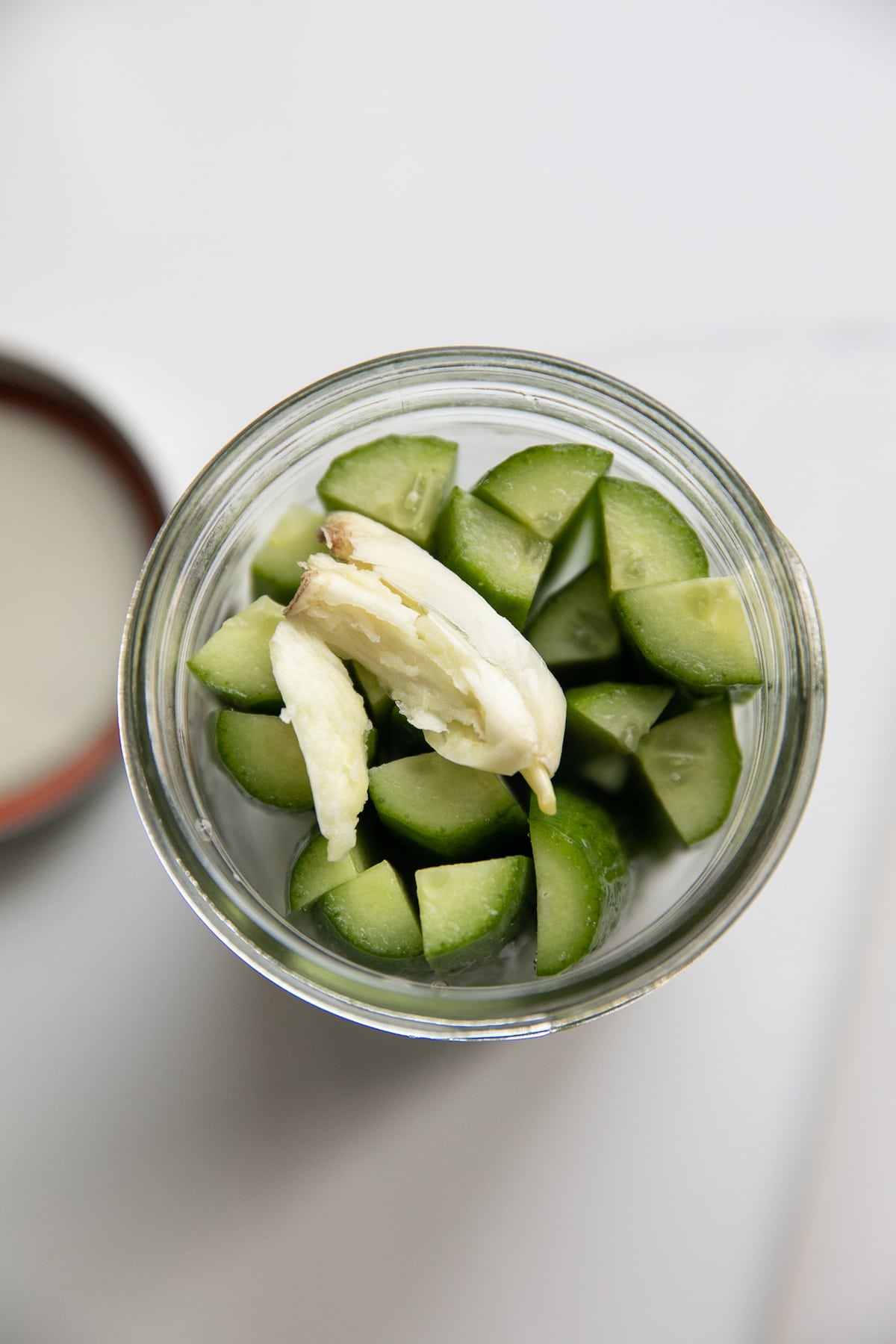 cut cucumbers in jar with garlic clove