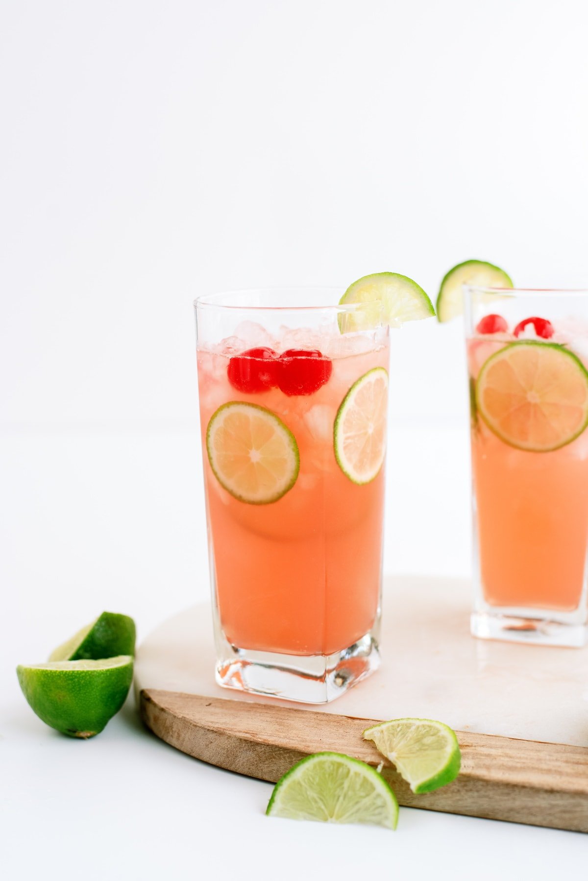 cherry limeade in a glass with lemon wedges
