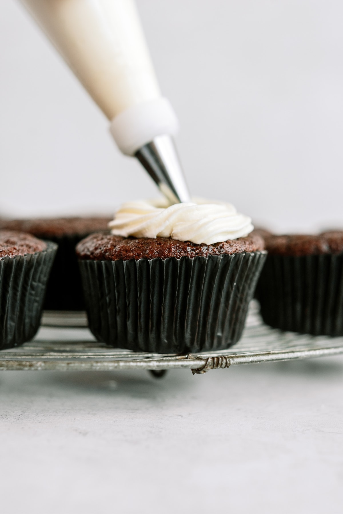 chocolate-cupcakes-with-vanilla-frosting being frosted