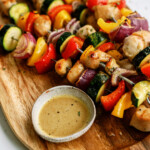 honey-soy-chicken-kabobs on oval wooden tray with bowl of sauce