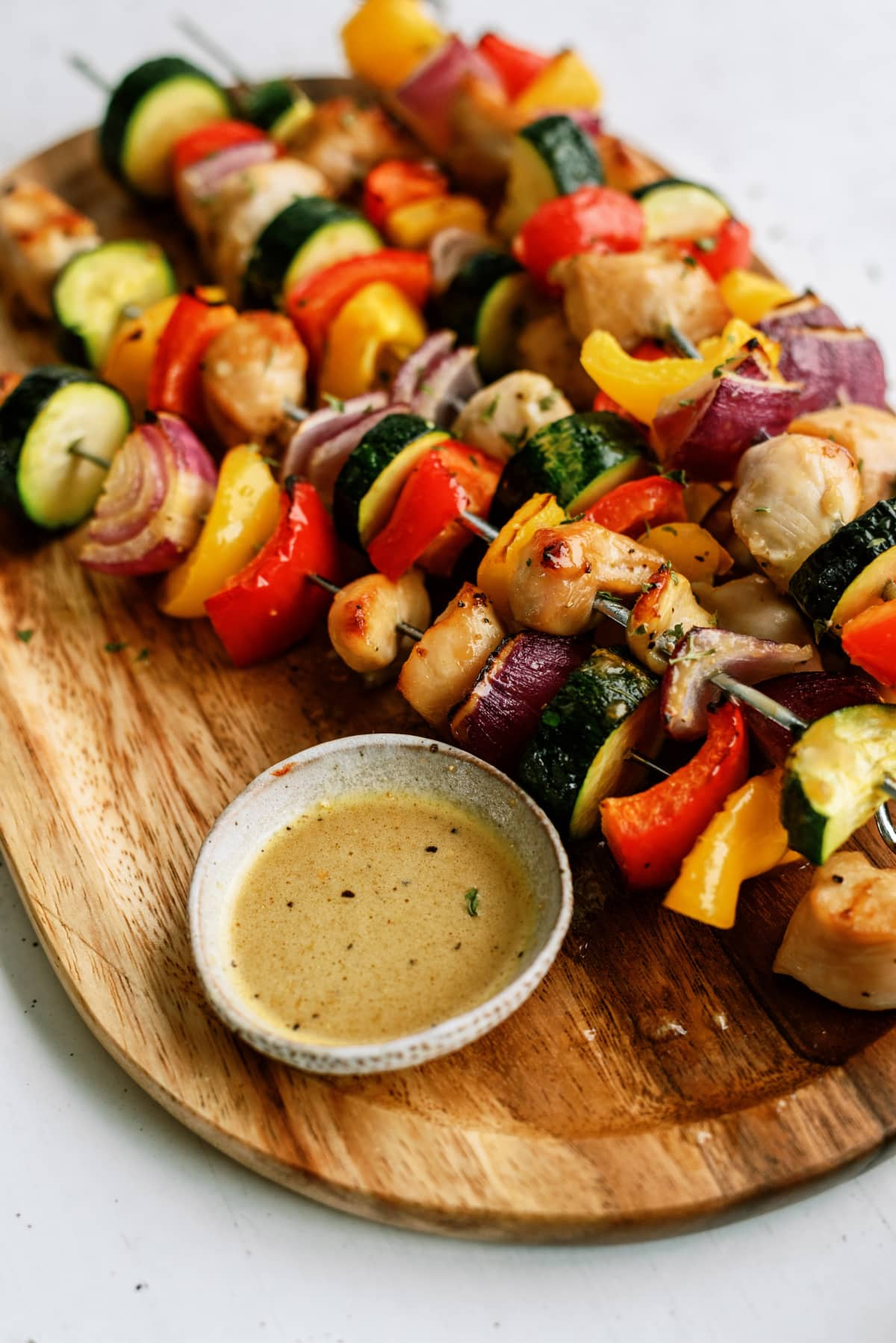 honey-soy-chicken-kabobs on oval wooden tray with bowl of sauce