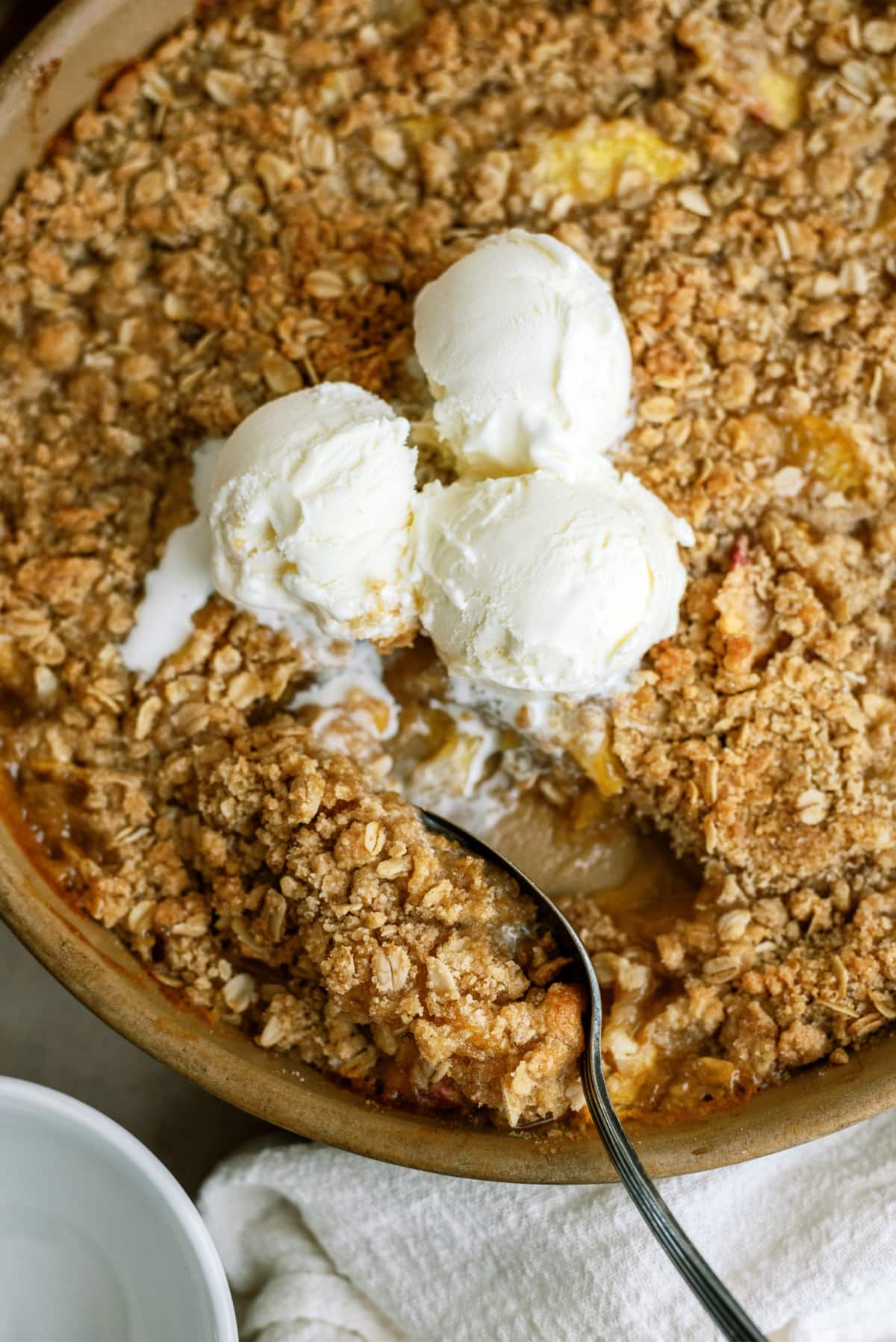 peach-crisp in pan with spoon and ice cream
