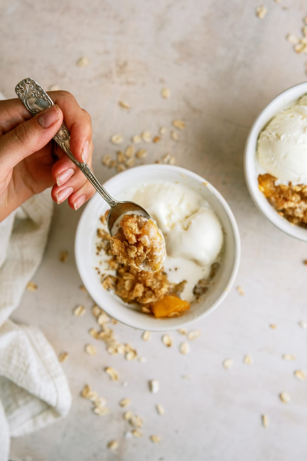 peach-crisp in bowl with someone spooning it out