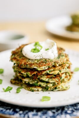 stack of zucchini-fritters on plates with sauce