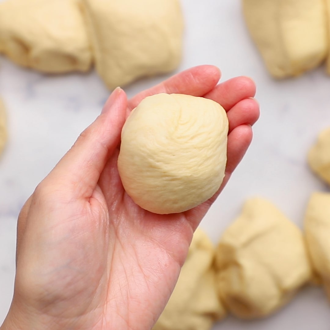 hand holding raw dinner roll dough