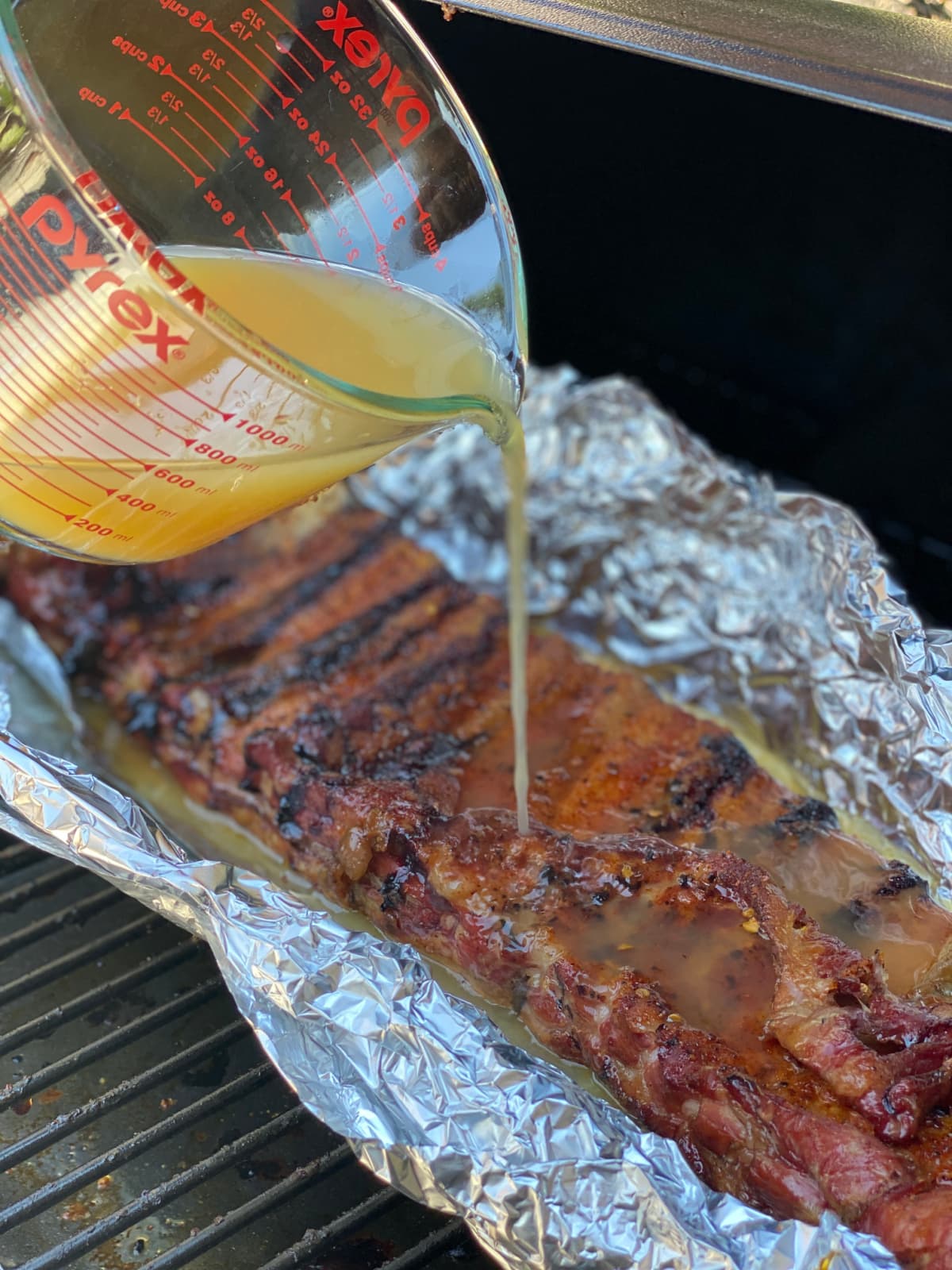 Smoked Ribs in Foil with Apple Juice being poured on top