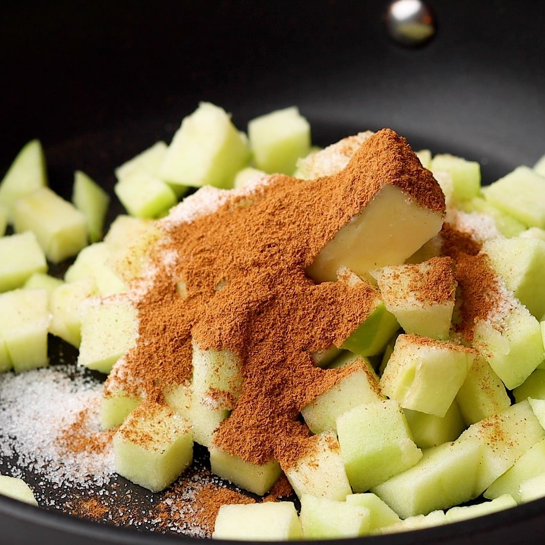 Raw green apple with sugar and cinnamon in pan