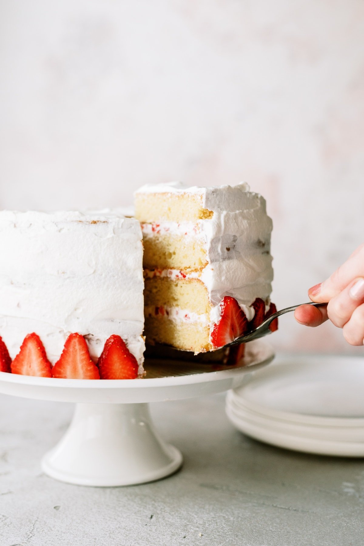 woman taking slice out of strawberry cake