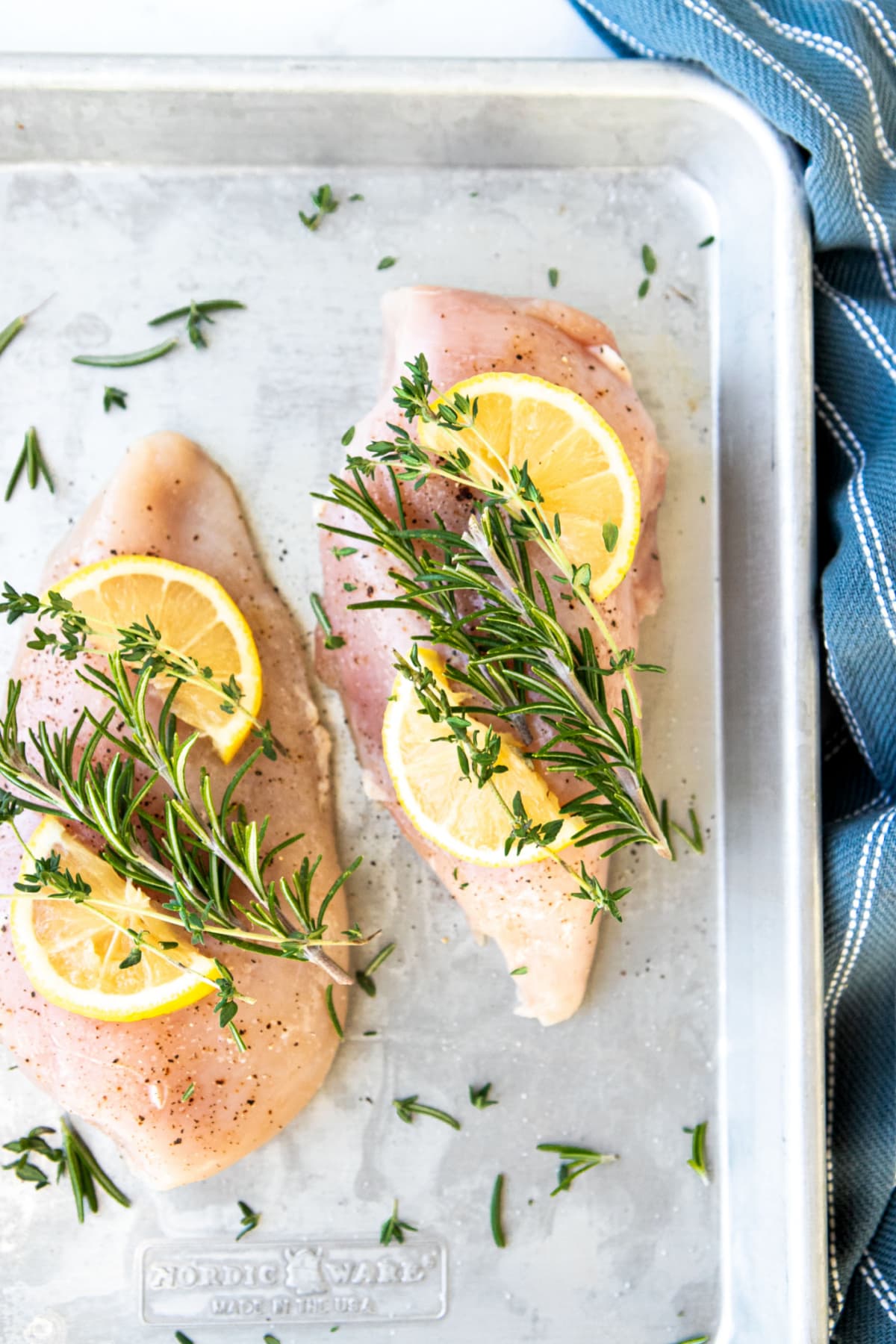 Raw Chicken on sheet pan with lemons and herbs