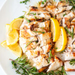 Sliced Sous Vide Chicken on plate with lemons and herbs