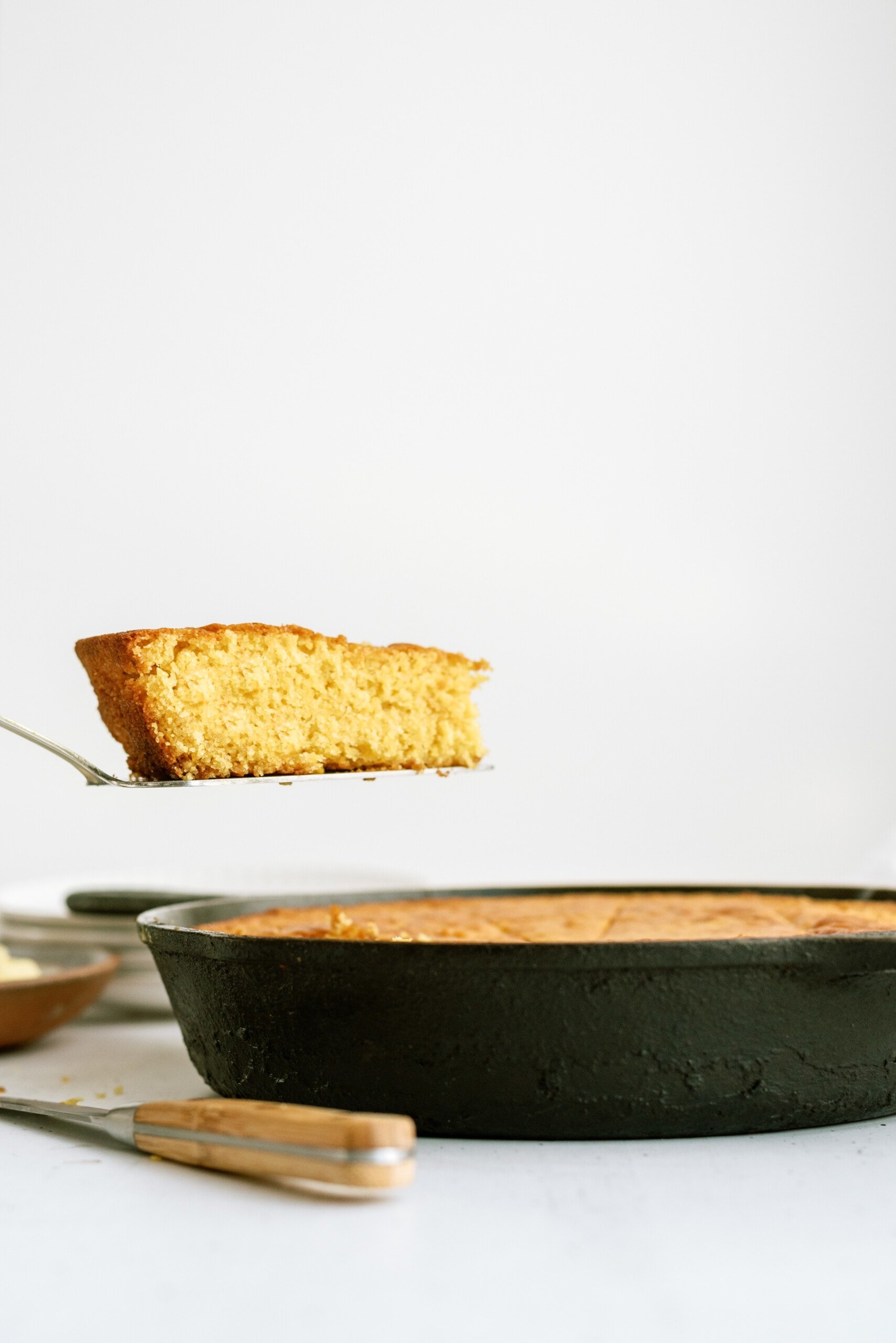 piece of cornbread being spatulad out from a cast iron skillet