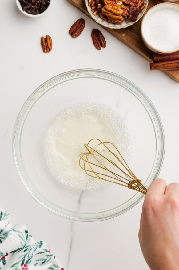 woman's hand whisking candied pecans ingredients in bowl