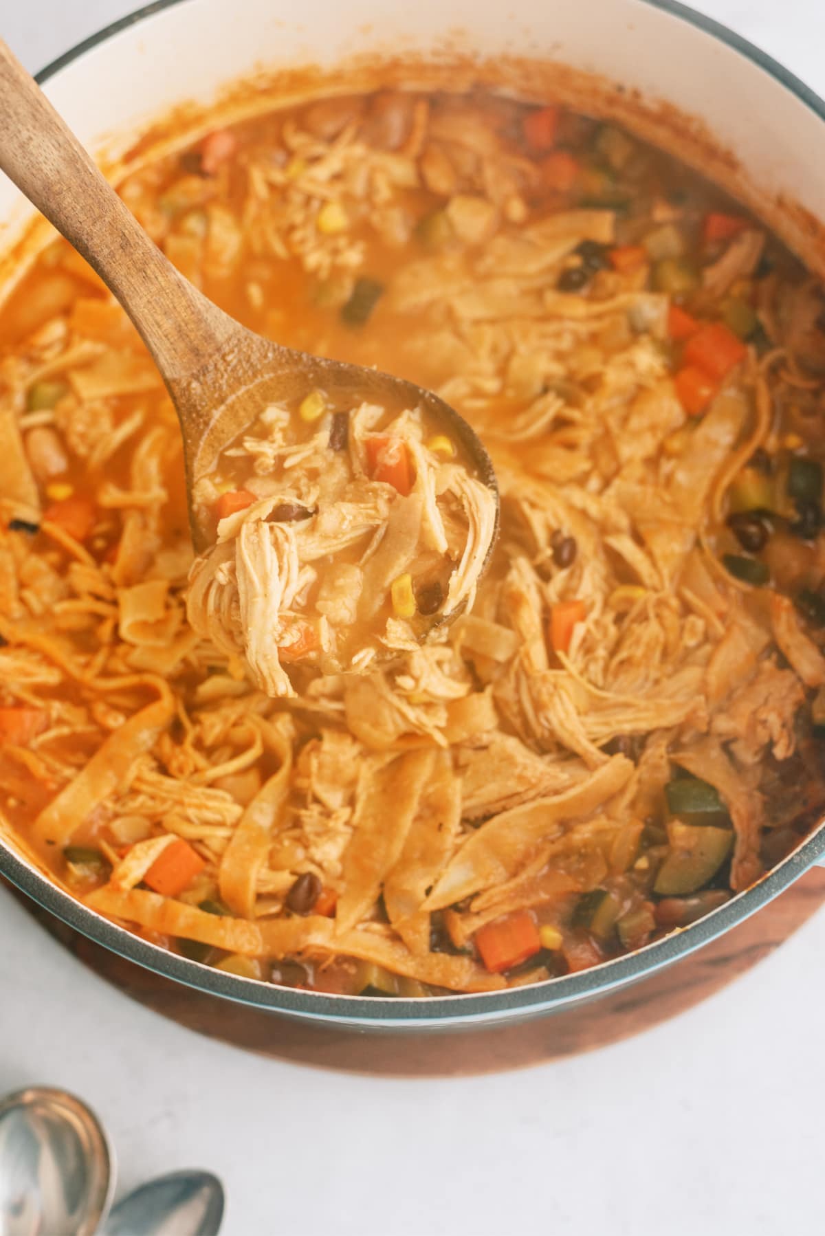 chicken-tortilla-soup in pot with wooden spoon