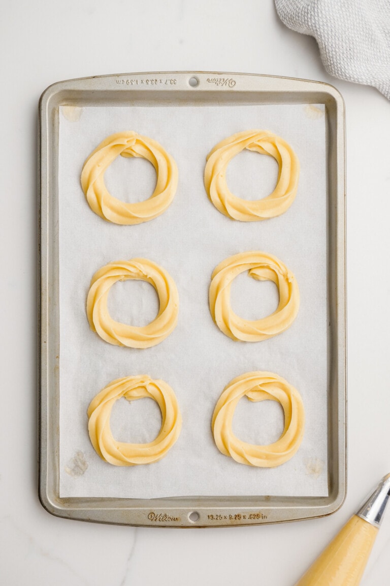 french cruller dough piped out onto baking sheet