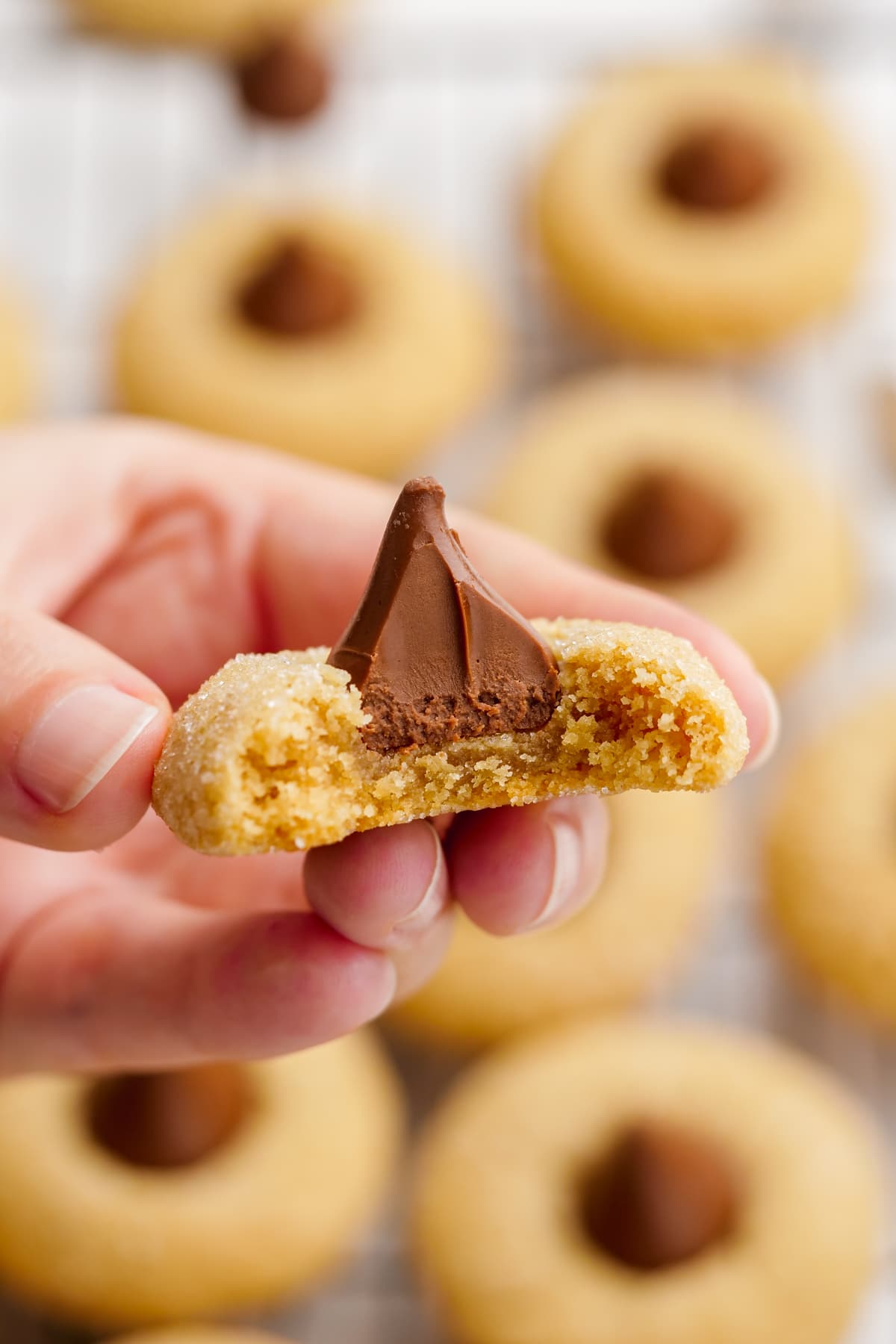 woman's hand holding peanut butter blossoms with bite taken out