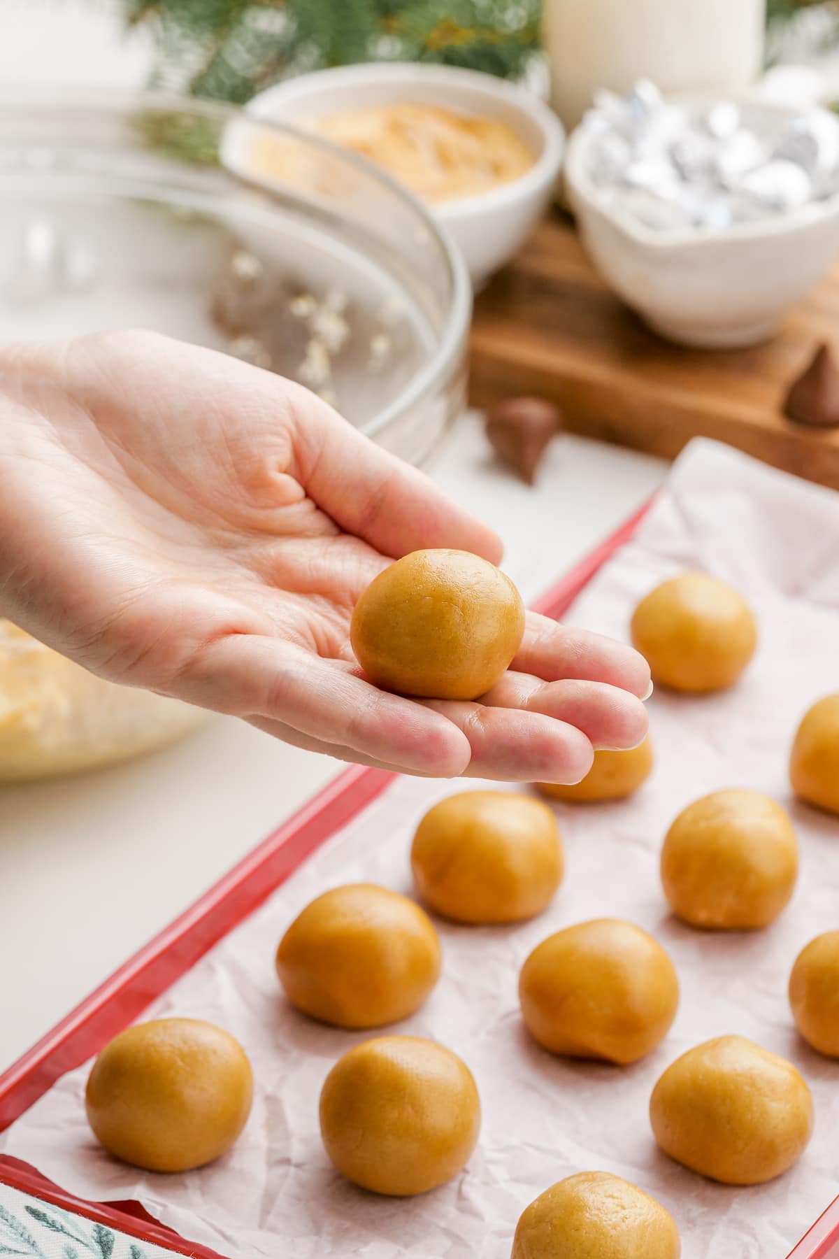 woman's hands placing peanut butter blossoms dough balls onto baking sheet