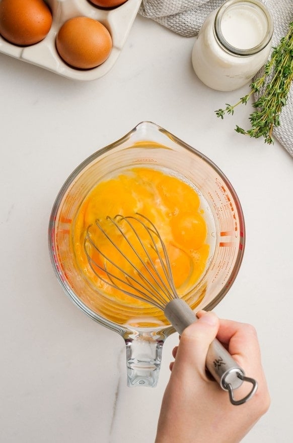 woman's hand whisking eggs in measuring cup