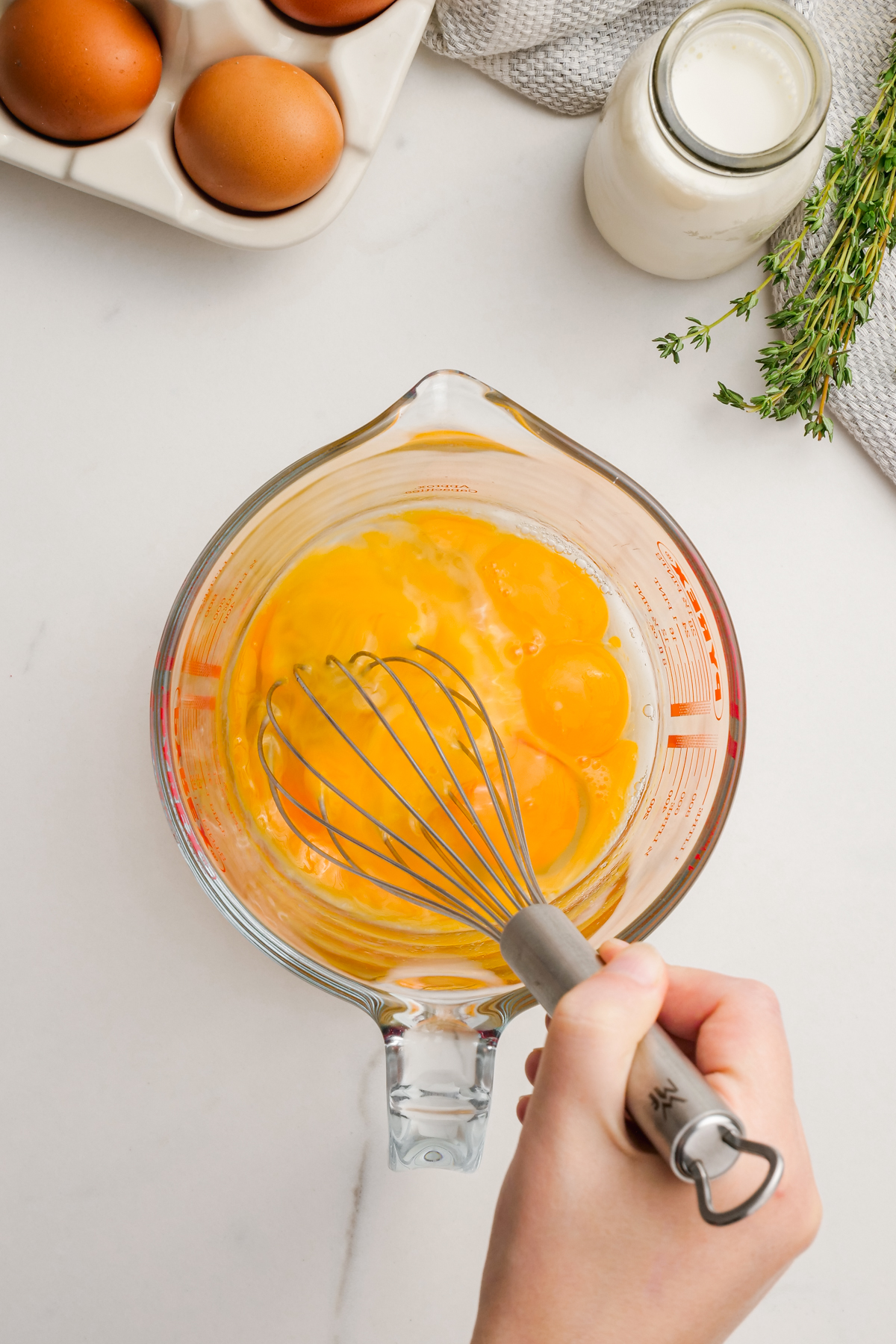 woman's hand whisking eggs in measuring cup