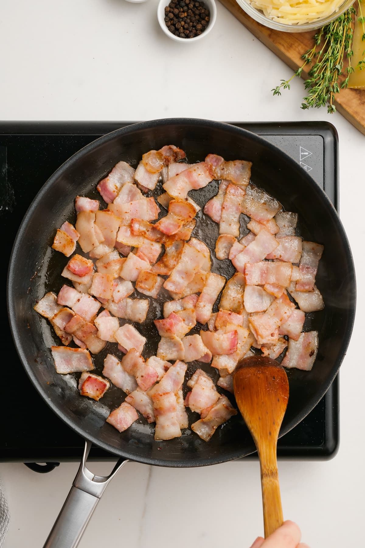 woman cooking bacon in cast iron skillet
