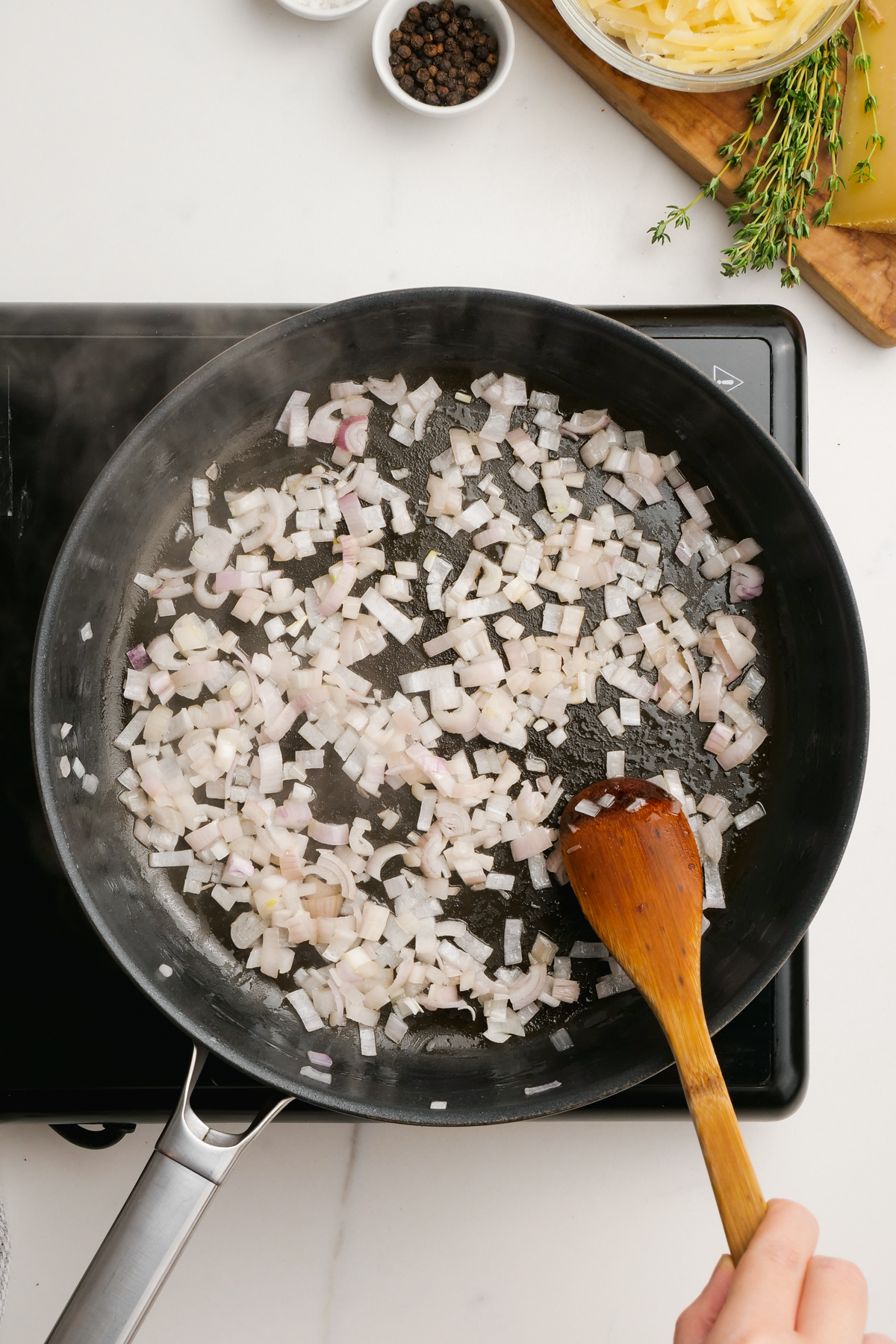 woman cooking diced shallot in skillet