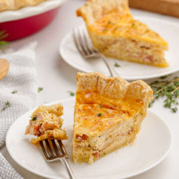 piece of quiche lorraine on plate with fork and bite taken
