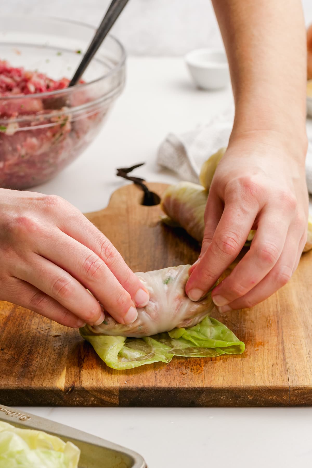 woman's hand rolling cabbage roll filling into leaf