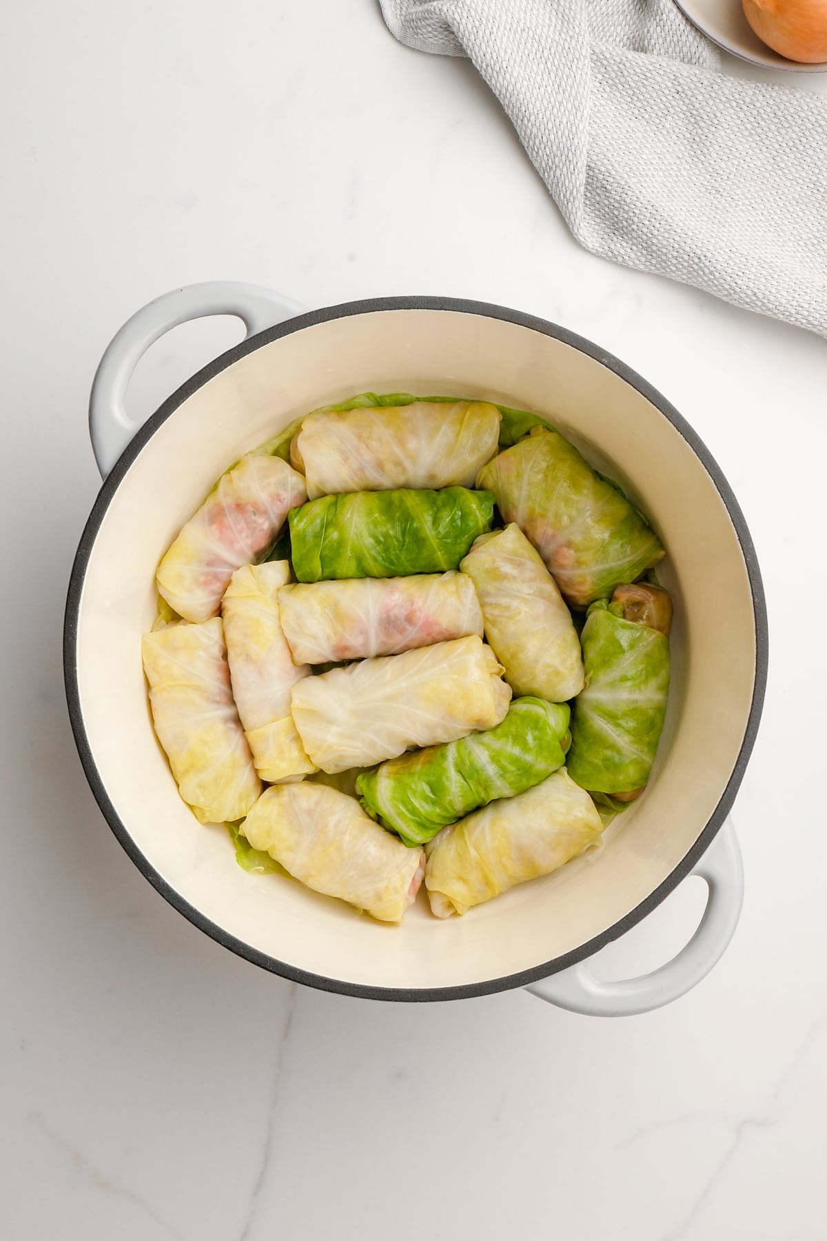 raw cabbage rolls layered in bottom of dutch oven