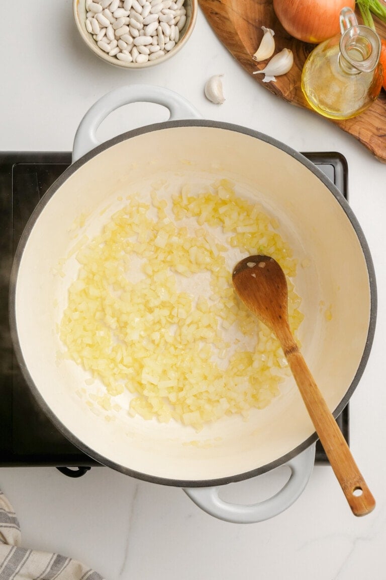 cooked onions in pot with wooden spoon